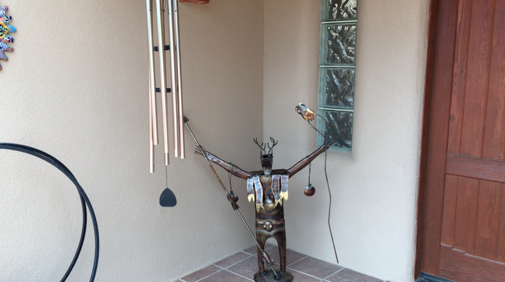 Metal shaman figure with deer head and antlers holding a spear and staff with an owl.